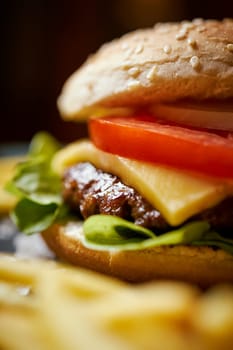 delicious cheeseburger surrounded by french fries on a black table