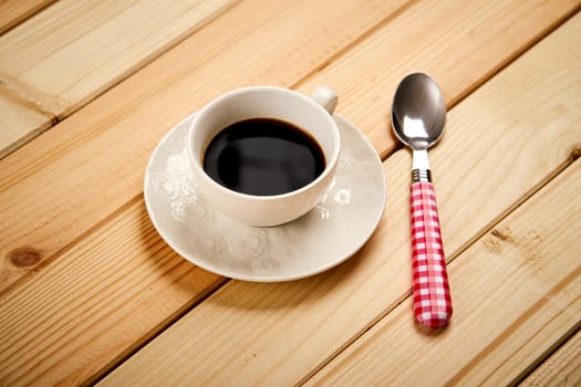 White cup with aromatic black coffee on wooden bright table
