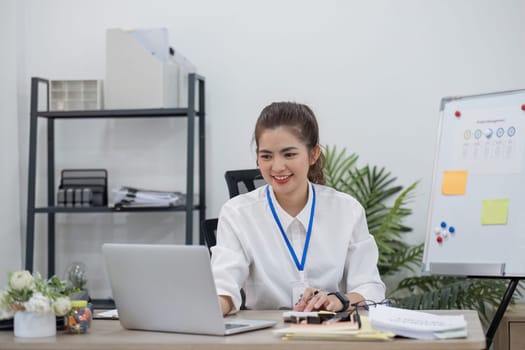 Beautiful determined business woman working using laptop recording data in modern office.