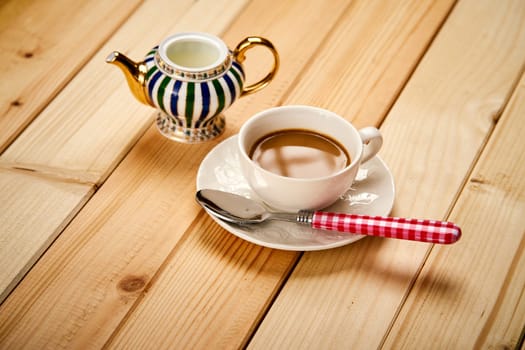 One small cup with aromatic coffee with milk on wooden bright table