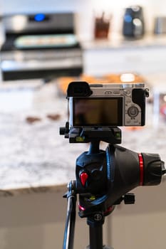 A DSLR camera, set up in a sleek, modern kitchen, captures the making of a video recipe for vlogging.
