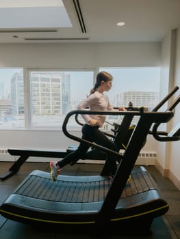 A dedicated young athlete giving her all, running on a treadmill in the gym.