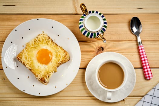 Delicious breakfast set with coffee and toast with fried egg on wooden kitchen table
