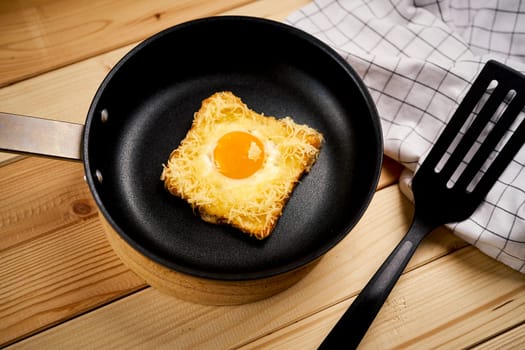 Delicious toast with fried egg and cheese in pan on wooden kitchen table