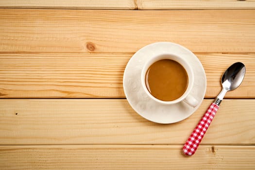 One small cup with aromatic coffee with milk on wooden bright table