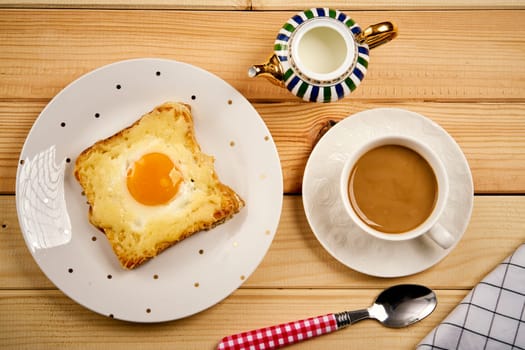 Delicious breakfast set with coffee and toast with fried egg on wooden kitchen table