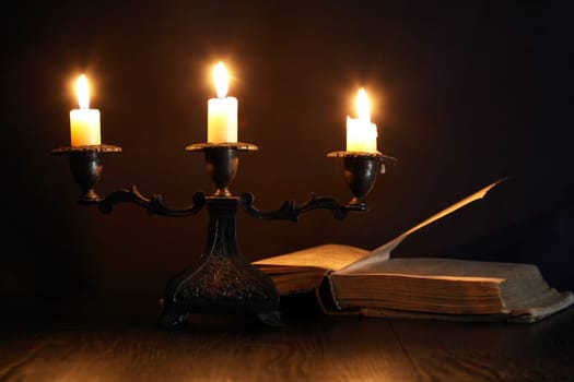 Nice vintage candlestick with lighting candle near old book