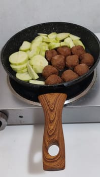 green zucchini and cutlets meatballs in a frying pan, homemade food, cooking. High quality photo