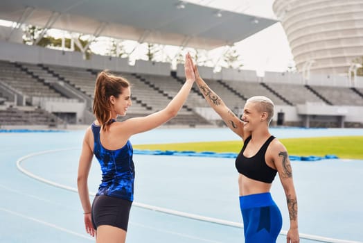 High five, sports and athletes on outdoor track, celebrate and winners of running competition. People, happy women and together for fitness at stadium, cardio and success at practice or training.