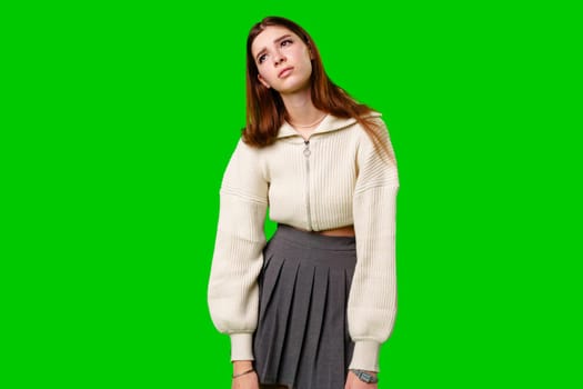 A woman wearing a skirt and sweater stands confidently against a vibrant green background. Her posture exudes strength and poise as she gazes ahead.