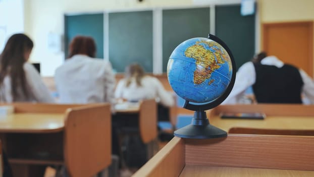 A globe of the world with textbooks in the background of a lesson in a school classroom