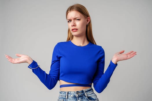 Young Woman in Blue Top Holding Out Hands in studio