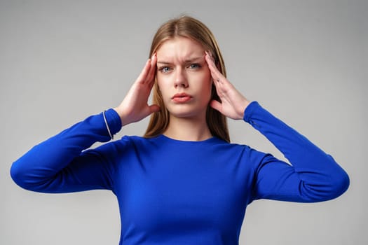 Young Woman in Blue Top Holding Hands to Ears in studio