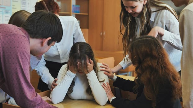 A high school girl cries and her friends comfort her