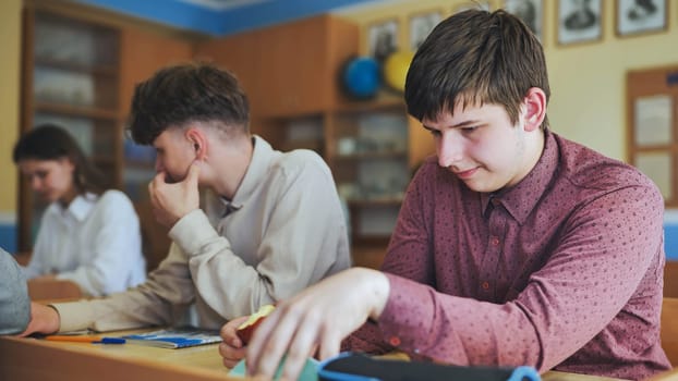 Schoolboys at a desk during class. The boy eats an apple