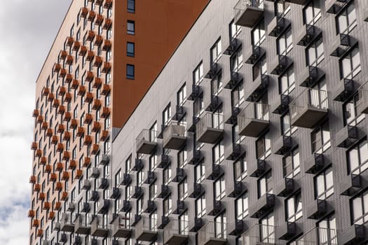 Residential complex in Moscow. New buildings in Moscow, high-rise bright creative house and against the sky. There are many apartments with Windows.