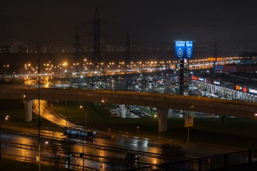 March 16, 2024, Moscow, Russia. On night roads, cars drive over a bridge and a road junction. Urban cityscape concept or abstract of advanced innovation, financial technology, energy power.