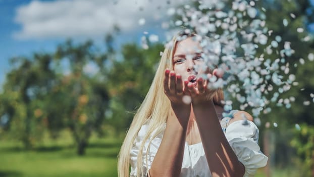 A girl blows a multi-coloured paper confetti out of her hands