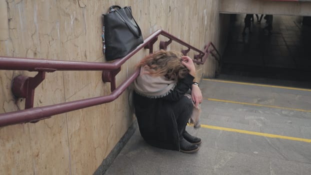 A young girl crying by the stairs in the subway