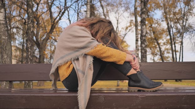 A young girl crying on a park bench in the fall