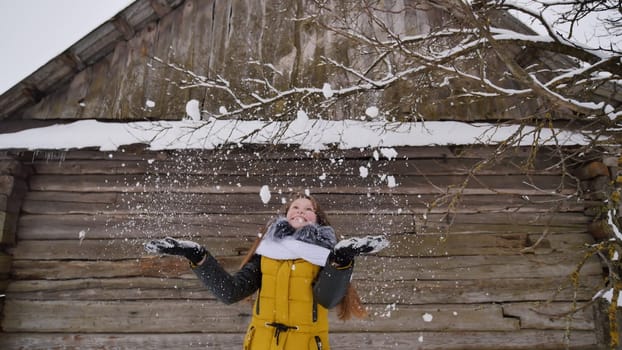 A young girl tossing snow in the winter in the countryside