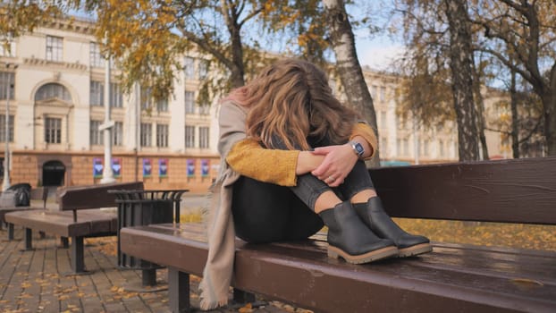 A young girl crying on a park bench in the fall