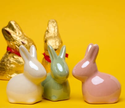 Ceramic decorative bunnies on a yellow background, festive Easter background