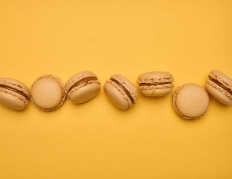 Chocolate macarons on a yellow background, dessert. Top view