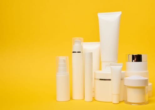 Various types of white plastic packaging, bottle, jar, tube on a yellow background. Container for cosmetics, copy space