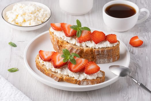 Homemade Crispbread toast with Cottage Cheese and Strawberry on white wooden board.