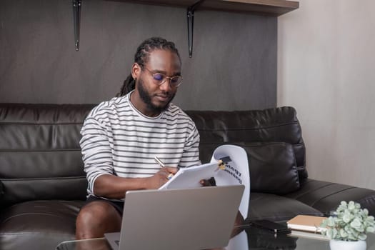 Young African American businessman spends his free time working from home on his laptop..