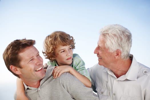 Grandfather, father and child by blue sky with smile for bonding, relationship and relax together. Family, generations and grandpa, dad and young boy on shoulders for holiday, vacation and weekend.