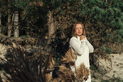 A woman standing in a forest surrounded by tall trees.