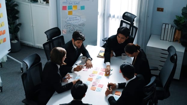 Top view of business people brainstorm idea by using sticky notes while planning marketing strategy at meeting room. Group of diverse team discuss about financial plan. Teamwork concept. Directorate.