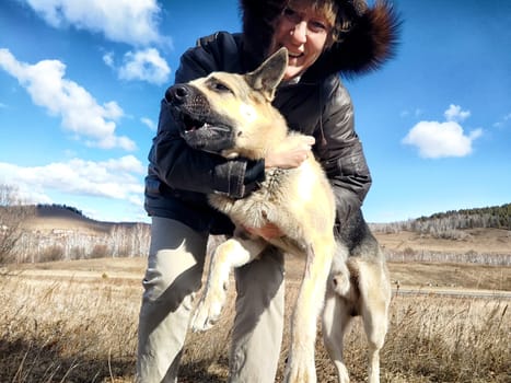 Adult girl or middle aged woman with shepherd dog in an autumn day