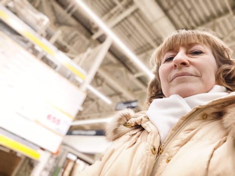 Middle-Aged Woman Shopping at a Warehouse Store. Woman browsing in large retail store aisle