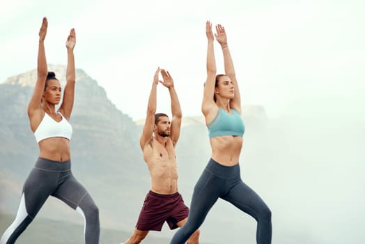 People, stretching and yoga outdoor for exercise, fitness and mindfulness or wellness at beach. Training, friends or man and women meditate for flexibility, spiritual strength and mental health.