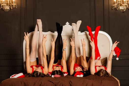 Four pretty young women with curly hair and red Christmas lingerie. New year background.