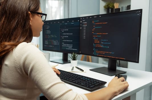 IT developer woman coding on laptop screen at back side view, creating social media website system automatically reply to customer, thinking program update data center at modern office. Postulate.