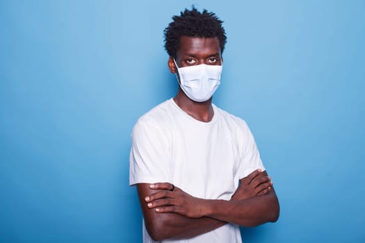 Portrait of african american man wearing face mask to protect from coronavirus in studio. Close-up of black male individual looking at camera while having protective mask on face.