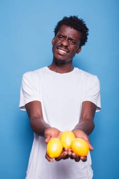 African american person holding lemons for healthy vegetarian diet. Man presenting yellow citrus fruits in hands for natural nutrition with vitamins. Adult showing fresh juicy fruits to camera.