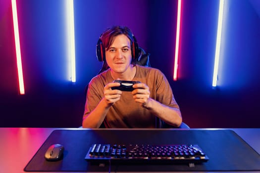 Enjoy smart gaming streamer with control joystick, playing game online of live streaming social media group with team skilled players on computer at modern technology cyber neon light room. Pecuniary.