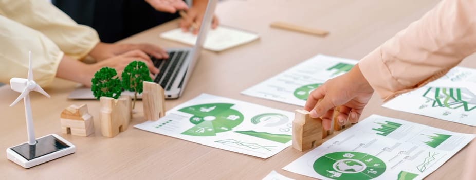 Environmental documents and a windmill model representing the use of clean energy are scattered on the table during a green business discussion about investing in clean energy. Closeup. Delineation.