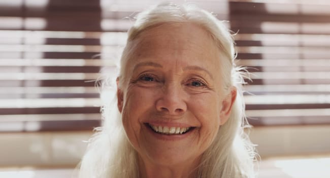 Senior woman, portrait and closeup in house by kitchen for retirement, memories and happiness. Elderly person, face and relax in nursing home on pension for mothers day, peace and calm with smile.