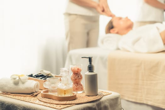 Aromatherapy massage on daylight ambiance or spa salon composition setup with focus decor and spa accessories on blur woman enjoying blissful aroma spa massage in resort or hotel background. Quiescent