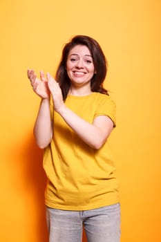 Cheerful female individual clapping hands to celebrate achievement while looking at camera. Caucasian woman with positive emotions applauding and doing appreciation claps for her friend.
