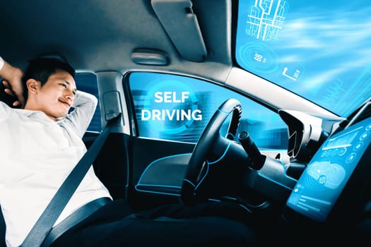 Self-driving autonomous car with relaxed young man sitting at driver seat is driving on busy highway road in the city. Concept of machine learning, artificial intelligence and augmented reality. uds