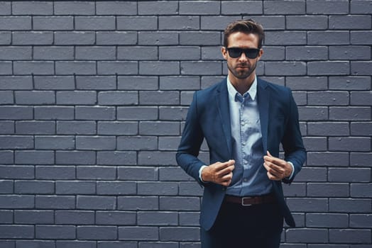 Confident, man and wall in suit with sunglasses for fashion, style and trendy in outdoor. Male person, pride and project manager for work, corporate and career on grey background in New York City.