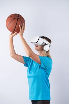Girl wearing visual reality glasses and casual cloth and holding basketball. Caucasian woman playing basketball while standing at pink background at sport arena hologram. Innovation. Contraption.