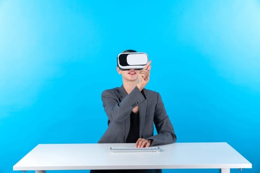 Smart manager wearing VR glasses while sitting at table with keyboard. Businesswoman pointing to manage data analysis while using suit and visual reality headset and enter in metaverse. Contraption.